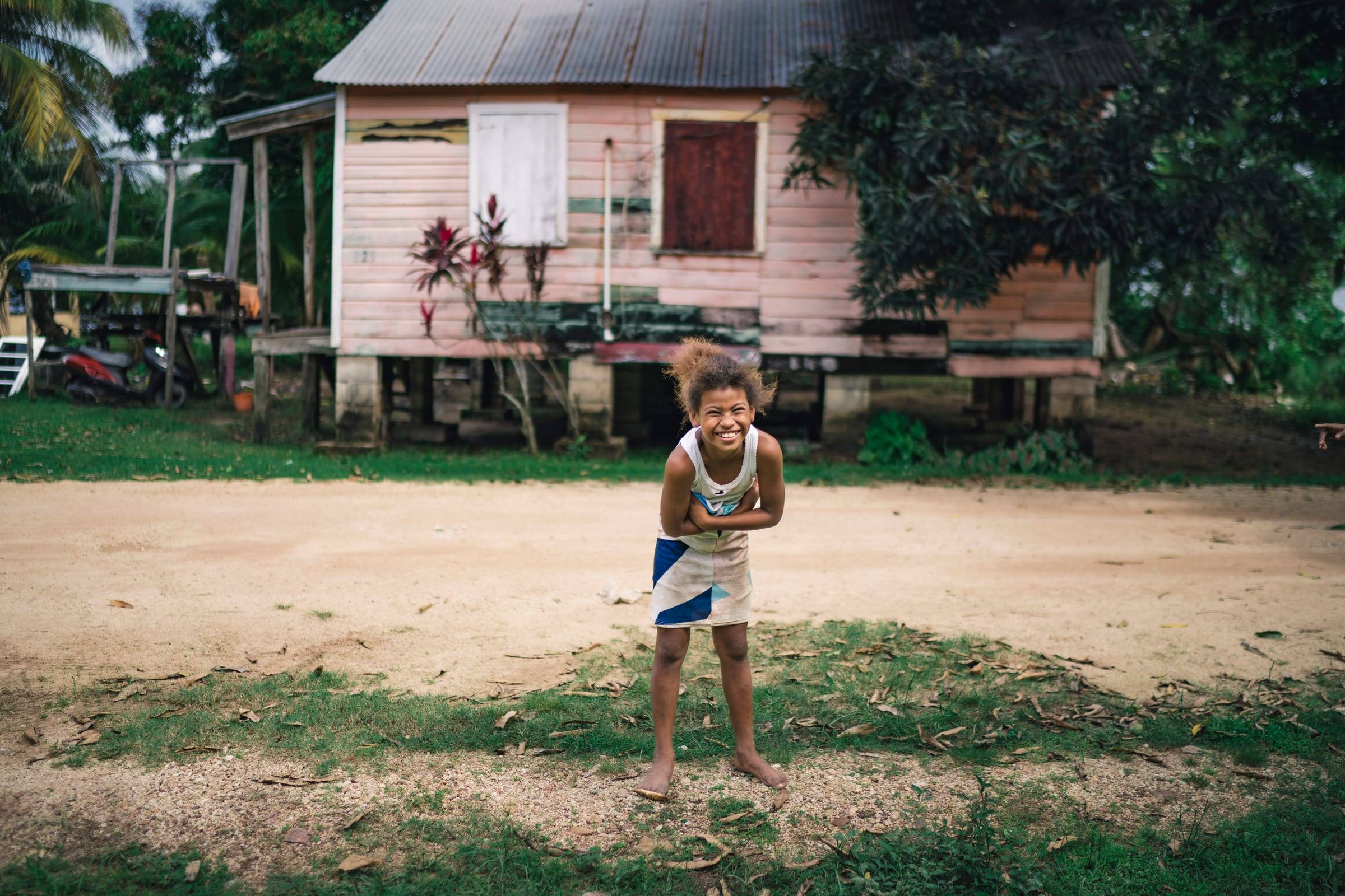 A girl laughs with her arms crossed in front of her pink stilt home