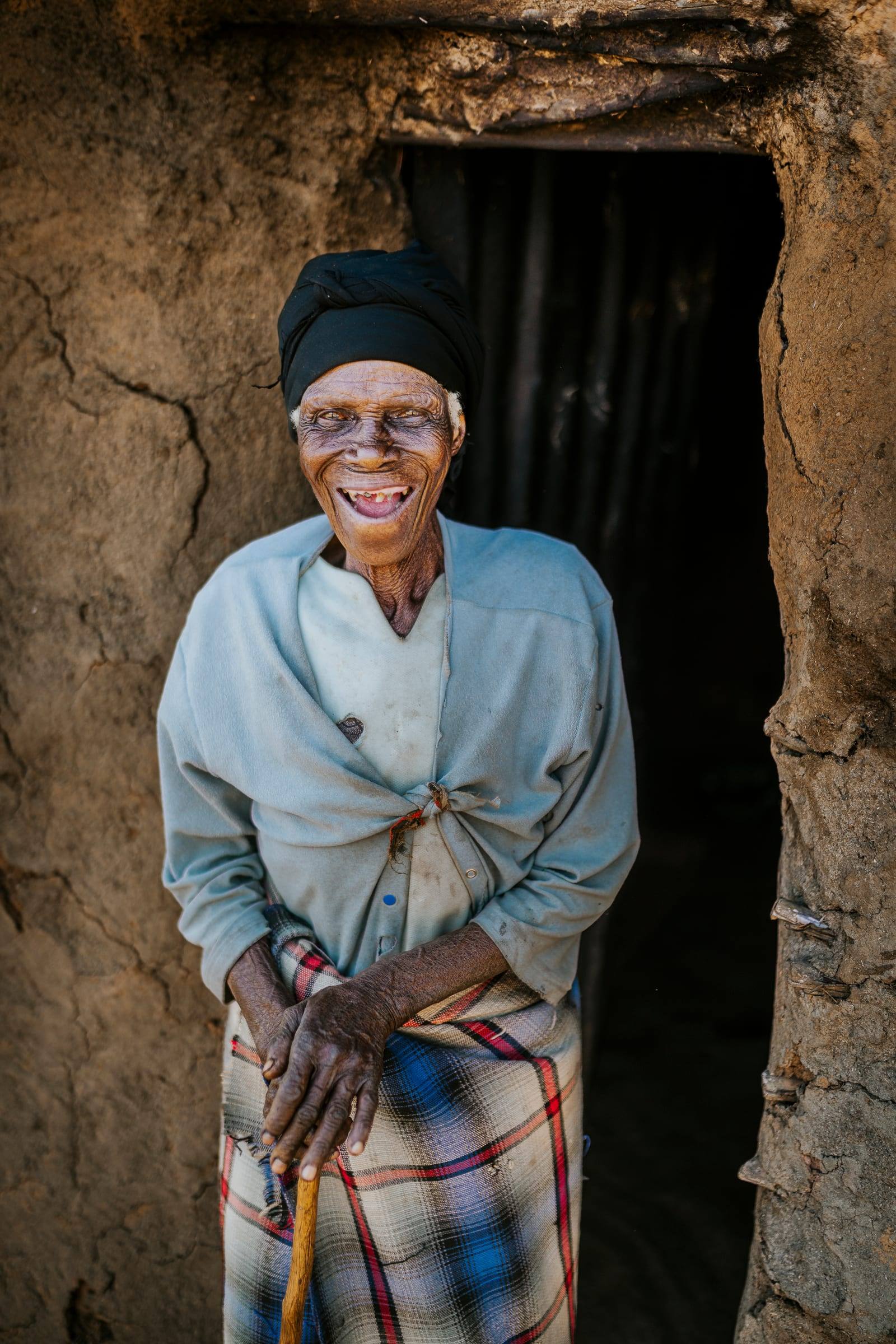 A grandmother laughs in the doorway of her home