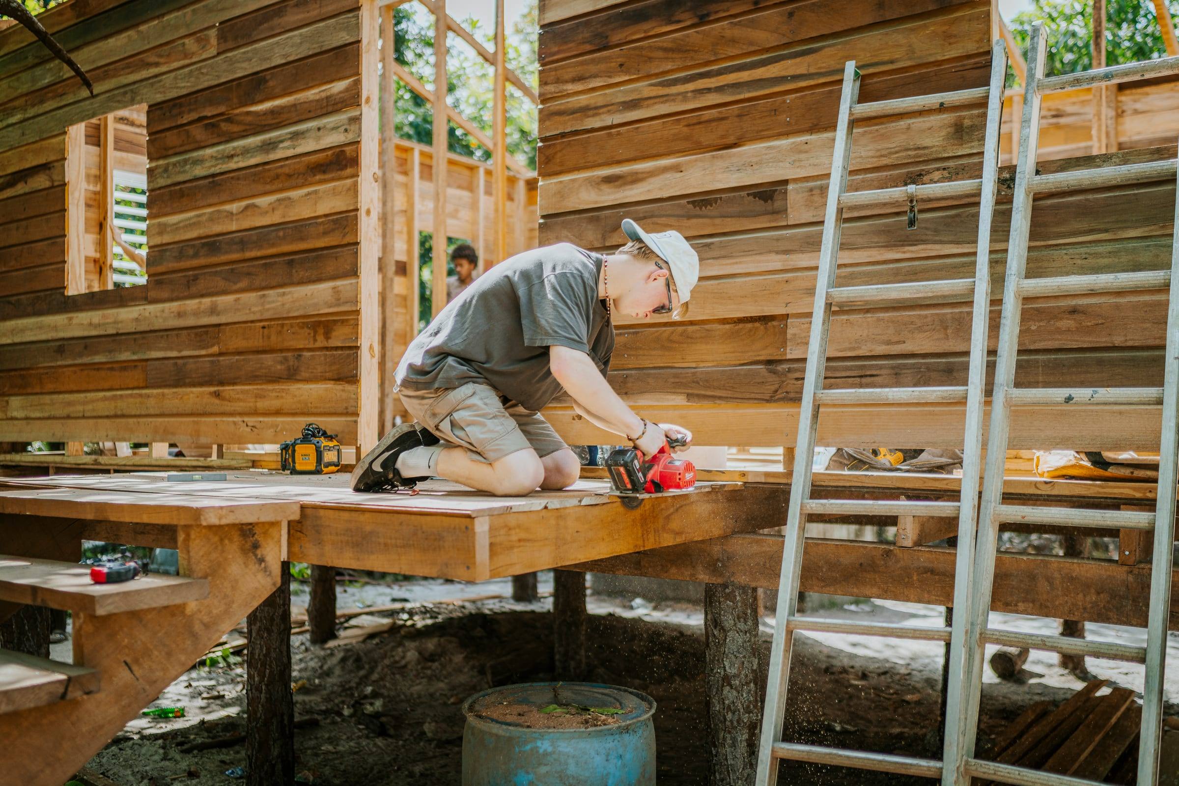 A volunteer measures boards on the floor of a new wooden home
