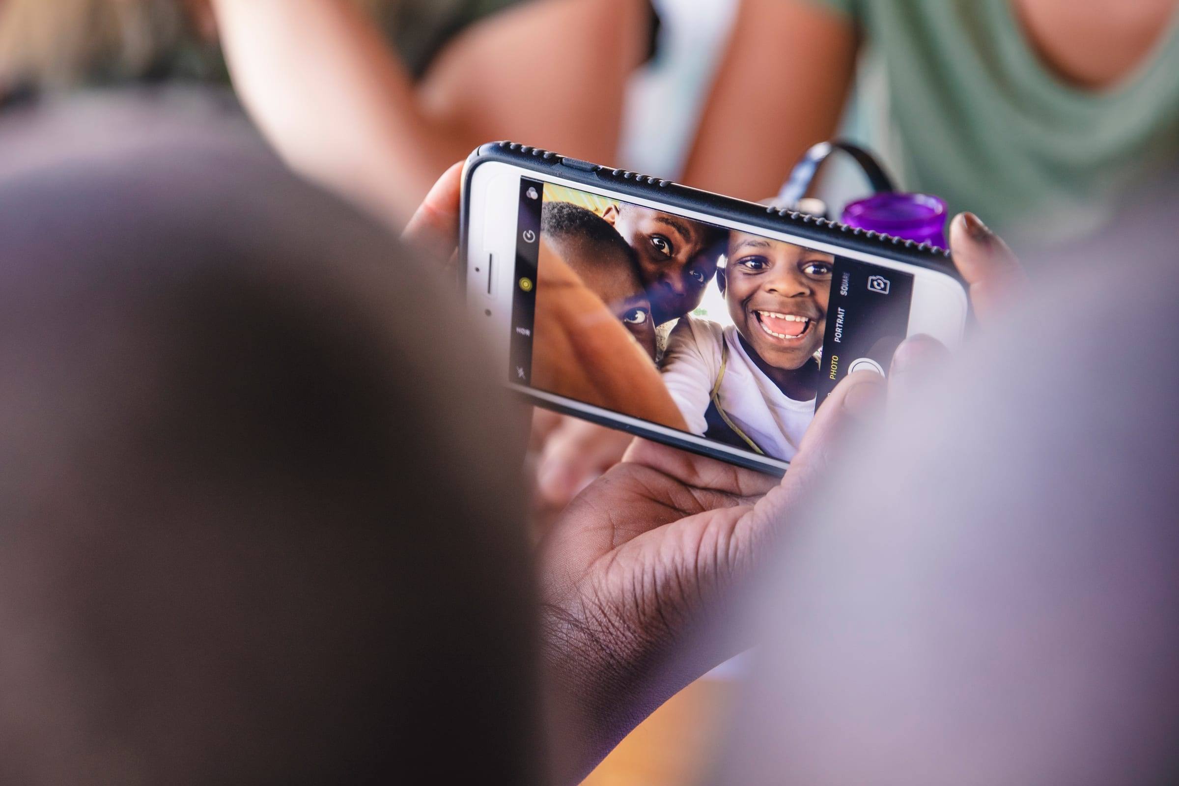 Children crowd around a phone to see a photo of themselves